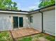 Side view of a gray home featuring a small backyard wood deck and glass sliding door entry at 3161 Normandy Rd, Indianapolis, IN 46222