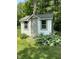 White outdoor shed with gray trim and shingled roof surrounded by lush green landscaping at 386 Shadow Hill Dr, Greenwood, IN 46142