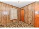 A cozy bedroom features unique wood paneling, vintage carpet, and a traditional door at 415 N 3Rd St, Elwood, IN 46036