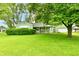 Charming single-story home with green exterior, a well-manicured lawn, and mature shade trees at 415 N 3Rd St, Elwood, IN 46036