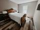 Bedroom with hardwood floors, white bedding, carved wooden headboard, and bright natural light from the window at 4635 Stansbury Ct, Indianapolis, IN 46254