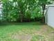 Large, tree-filled backyard with a mix of grass and ground cover and a view of the side of the house at 4747 Guion Rd, Indianapolis, IN 46254