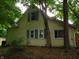 Exterior view of the home featuring a cream color siding with blue shutters surrounded by mature trees at 4747 Guion Rd, Indianapolis, IN 46254