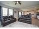 Spacious living room featuring a brown leather reclining sofa set, ceiling fan, and bright windows at 4832 W Safford Dr, New Palestine, IN 46163