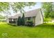 Back of house with green yard, bushes, and mulch at 5104 W Prairiewood Dr, Muncie, IN 47304