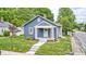 Charming blue home with a covered front porch, complemented by green grass and mature trees at 5203 Carrollton Ave, Indianapolis, IN 46220