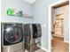 This laundry room features modern machines, ample space and shelving for laundry supplies near the bathroom at 5439 Maywood Dr, Whitestown, IN 46075