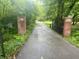 View of the private entrance to the home with brick pillars, iron gate, and mature trees at 6220 E 56Th St, Indianapolis, IN 46226
