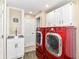 Bright laundry room with modern red appliances and white cabinets for convenient storage at 6220 E 56Th St, Indianapolis, IN 46226