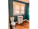 Updated bathroom featuring a pedestal sink, toilet, updated flooring, and a window for natural light at 624 N Rural St, Indianapolis, IN 46201
