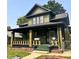 Charming two-story home with a covered porch, green grass, and mature trees at 624 N Rural St, Indianapolis, IN 46201