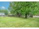 Large grassy backyard with mature trees, framed by a wooden fence, ideal for outdoor activities at 6837 Littleton Dr, Indianapolis, IN 46221