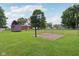 View of the backyard, including an outbuilding, basketball hoop, chain link fence, and green lawn at 9974 N 850 W, Fairland, IN 46126