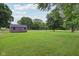 Expansive backyard featuring lush lawn, outbuilding, mature trees, and open space at 9974 N 850 W, Fairland, IN 46126