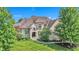 Elegant stone home featuring a lush green lawn, mature trees, and a welcoming arched entrance at 10471 Winghaven Dr, Noblesville, IN 46060