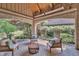 Covered brick patio with outdoor seating offers a view of the lawn and lake at 10471 Winghaven Dr, Noblesville, IN 46060