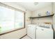 Efficient laundry room with a window, washer, dryer, and shelving for storage, providing convenience at 1111 Pendle Hill Ave, Pendleton, IN 46064
