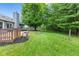 A beautiful backyard featuring a wooden deck, fire pit, mature trees, and well-maintained lawn offers a tranquil outdoor space at 11218 Baycreek Dr, Indianapolis, IN 46236