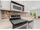 Well-lit kitchen features stainless steel microwave, oven, stove, white cabinets and a tiled backsplash at 11218 Baycreek Dr, Indianapolis, IN 46236