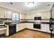 Traditional eat-in kitchen with wood cabinets, black appliances, and wooden floors at 116 Bennington Rd, Indianapolis, IN 46227