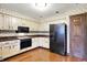 Traditional eat-in kitchen with wood cabinets, black appliances, and wooden floors at 116 Bennington Rd, Indianapolis, IN 46227