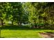 Lush backyard with mature trees, green grass, and access to a lake, perfect for outdoor recreation at 1229 Helford Ln, Carmel, IN 46032