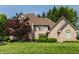 Charming brick home with a well-manicured lawn, lush trees, and a vibrant red front door at 1229 Helford Ln, Carmel, IN 46032