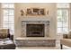 Close-up of a stone fireplace flanked by windows and seating in a bright living room at 1229 Helford Ln, Carmel, IN 46032