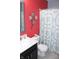 Bright bathroom featuring a white marble sink, toilet, and patterned shower curtain against a vibrant red wall at 12901 N Collett Way, Camby, IN 46113
