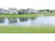 Scenic view of a pond with a well-maintained lawn and neighborhood homes in the background at 12901 N Collett Way, Camby, IN 46113
