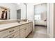 Bright bathroom featuring a double vanity with granite countertop and an open doorway to a bedroom at 13346 W Sherbern Dr, Carmel, IN 46032