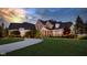 Stunning stone home with lush lawn, covered porch, and circular driveway at dusk at 13346 W Sherbern Dr, Carmel, IN 46032