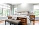 Beautiful main bedroom featuring large windows, hardwood floors, and a stylish upholstered bench at 13346 W Sherbern Dr, Carmel, IN 46032