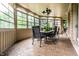 A sunroom with a table and chairs. The room has many windows with green tree views at 13346 W Sherbern Dr, Carmel, IN 46032