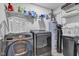 Modern laundry room featuring gray washer and dryer with storage shelves stocked with cleaning supplies at 13844 N Cardonia Dr, Camby, IN 46113