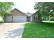 Charming brick home featuring an attached two-car garage and a well-manicured lawn at 1411 Mimosa Ct, Greenfield, IN 46140