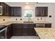 Modern kitchen featuring granite counters, stainless steel dishwasher, and sleek dark cabinetry at 14446 Chapelwood Ln, Fishers, IN 46037