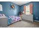 Stylish bedroom with a floral-patterned bedspread, blue walls, and a window that offers plenty of natural light at 1605 Perry Commons Blvd, Indianapolis, IN 46217