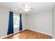 Bright bedroom with beautiful hardwood floors, ceiling fan, and large window with blue curtains at 18005 Gasparilla Ct, Westfield, IN 46062