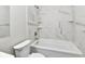 Modern bathroom featuring marble-look tiling surrounding a pristine white bathtub and shower at 2026 Spruce St, Indianapolis, IN 46203