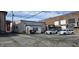Back parking lot features an older white building and a dumpster and parked cars at 22 W 8Th St, Anderson, IN 46016