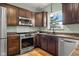 Well-lit kitchen featuring stainless steel appliances, tile backsplash, and dark wood cabinetry at 2247 Rolling Hill Ct, Columbus, IN 47201