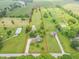 Wide aerial shot showcasing a home with multiple outbuildings surrounded by open green spaces and trees at 391 W 500 S, Anderson, IN 46013