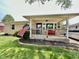 Inviting covered front porch with a vibrant red bench and manicured landscaping at 419 N 14Th Ave, Beech Grove, IN 46107