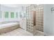 Well-lit bathroom featuring a jetted tub under windows, a privacy glass-block shower, and tiled floors at 545 Pitney Dr, Noblesville, IN 46062