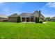 Well-manicured backyard with green lawn, privacy trees, and home with brick accents and a chimney at 648 Shakespeare Dr, Avon, IN 46123