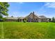 Large backyard with green lawn and mature trees surrounding a home with a brick chimney at 648 Shakespeare Dr, Avon, IN 46123