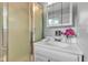 Bathroom featuring a shower, vanity, mirror, and vibrant pink flowers at 703 Chapel Hill W Dr, Indianapolis, IN 46214
