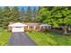 Red brick home with an attached garage, surrounded by a lush green lawn and mature trees, providing a serene setting at 703 Chapel Hill W Dr, Indianapolis, IN 46214