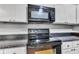 Modern kitchen with sleek black stove, microwave, and white cabinets offering functionality and style for any chef at 703 Chapel Hill W Dr, Indianapolis, IN 46214